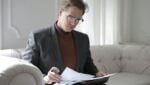 classy executive male reading papers on couch