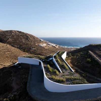 Muro Curvo de Pedra Secas Define Vila Projetada por A31 e Tom Dixon, Emergindo da Encosta de Mykonos.