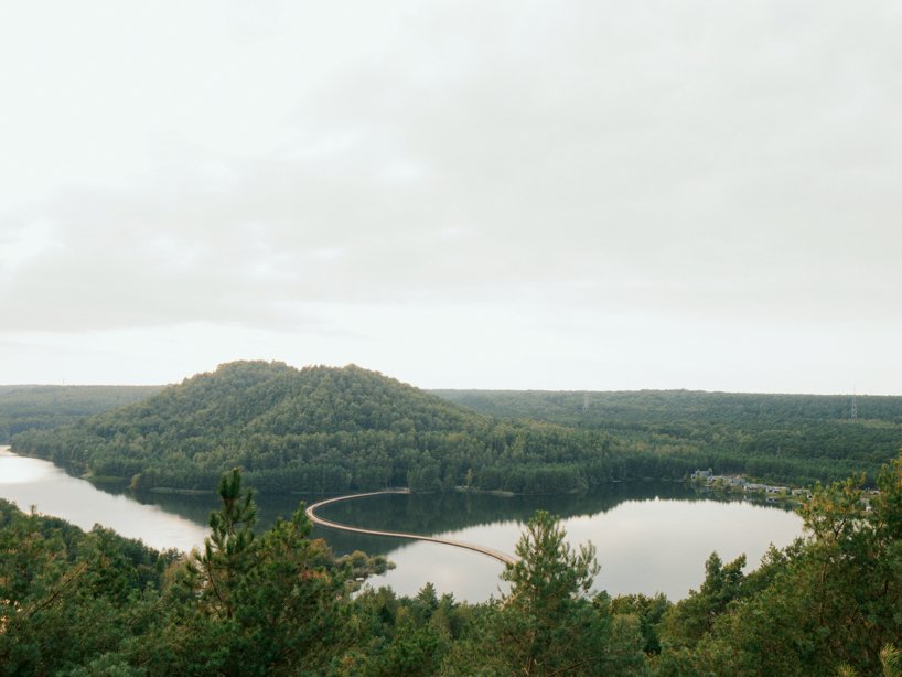 ponte ciclística flutuante se curva através do lago na Bélgica, adaptando-se aos níveis da água