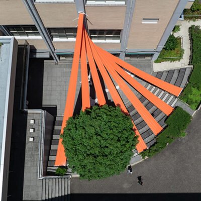 Painéis de tecido laranja brilhante se espalham acima do anfiteatro em terraços da universidade no Japão.